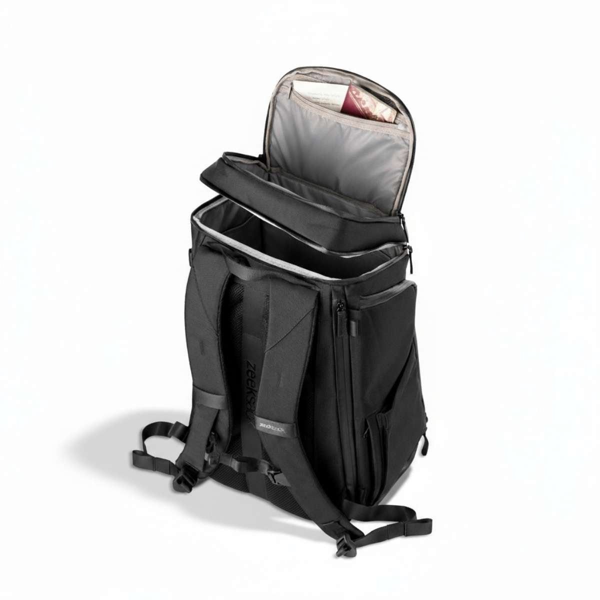 En svart ryggsäck sedd från sidan, står på golvet med det övre facket delvis öppet.