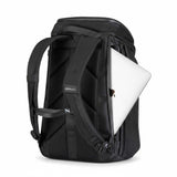 Svart ryggsäck med en silvrig laptop delvis inskjuten i sidofacket.